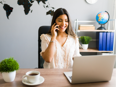 Woman in office talking on the phone in front of a laptop