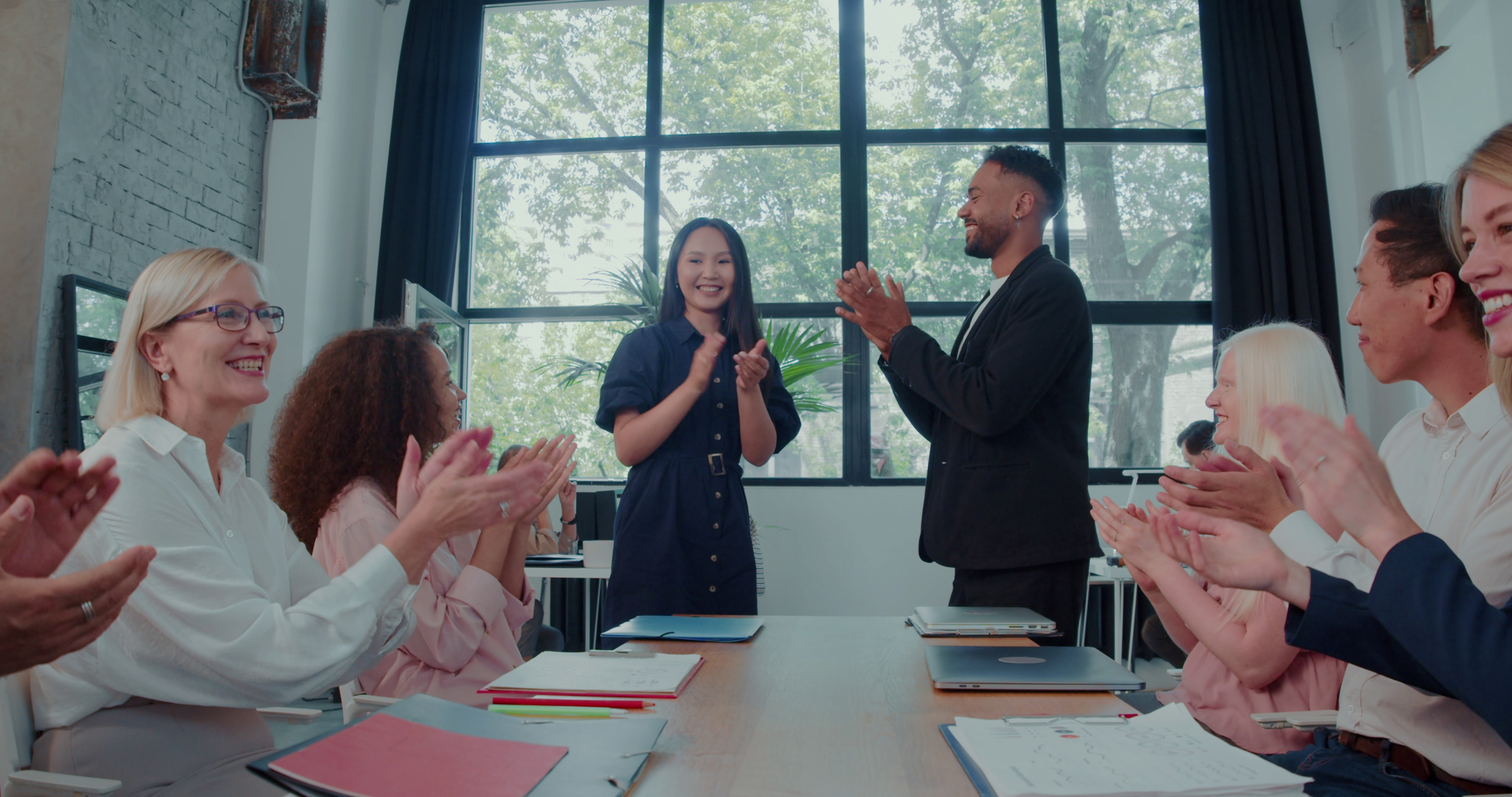 People sitting around a table during a meeting, clapping.